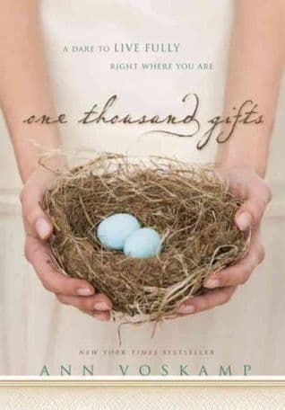 A pale linen-toned jacket showing two cupped hands holding a small bird's nest with two blue eggs, the script title 'one thousand gifts' across the middle and 'A DARE TO LIVE FULLY RIGHT WHERE YOU ARE' in small caps above it, ANN VOSKAMP set in capitals near the bottom.