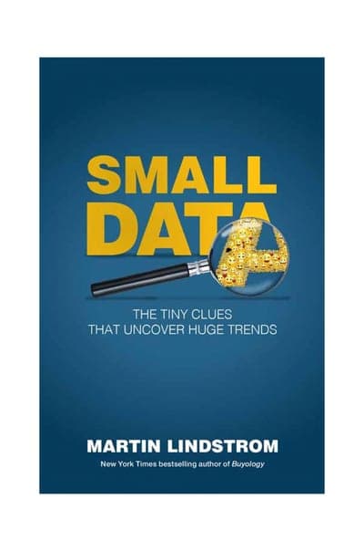 A dark teal-blue gradient field, the title SMALL DATA in bold yellow capitals at the top with a large yellow magnifying glass overlapping the lower letters and filled with tiny yellow face-emoji icons, the subtitle 'The Tiny Clues That Uncover Huge Trends' in white beneath it, and the author's name MARTIN LINDSTROM in bold white capitals near the bottom with 'New York Times bestselling author of Buyology' beneath it.