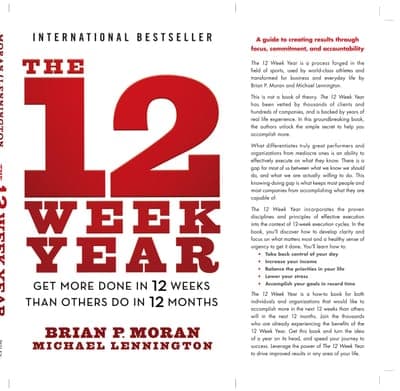 A full, unfolded white jacket: an 'INTERNATIONAL BESTSELLER' banner at top, the huge red numeral '12' stacked above 'WEEK YEAR' in bold black and red caps on the front panel, the authors' names beneath, and a red-highlighted descriptive blurb ('A guide to creating results through focus, commitment, and accountability') filling the back-cover panel to the left.