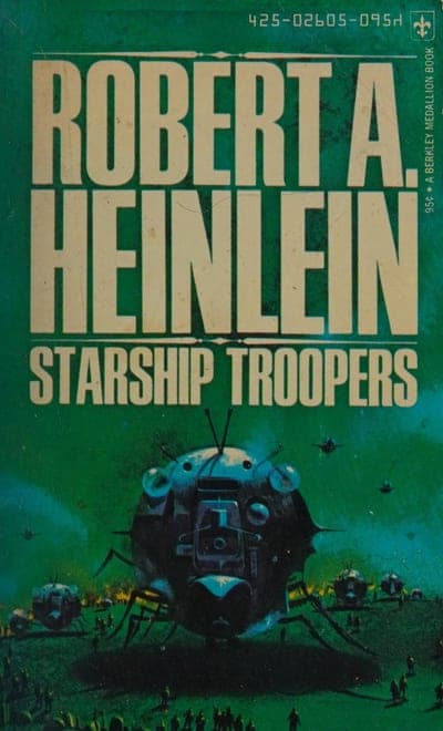 A Berkley Medallion paperback of Starship Troopers — a green field, the author's name in large cream block capitals across the top, the title in cream capitals below it, and a painted scene of a giant armored alien war-machine striding over a burning outpost with tiny armored troopers firing on it from the ground.