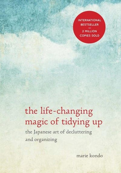 A pale, cloudy sky-blue field fading to cream at the bottom, a red circular seal at top right reading 'International Bestseller — 2 Million Copies Sold,' the title 'the life-changing magic of tidying up' in red lowercase serif type, the subtitle 'the Japanese art of decluttering and organizing' beneath it in grey, and the author's name 'marie kondo' in small grey lowercase at the bottom right.