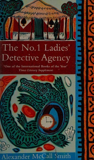 A UK paperback with a colorful African batik/lino-cut-style illustration and an orange-and-black geometric border running down the right edge; the top third shows a thatched-roof building with striped columns and a robed figure standing outside; the title runs in white serif type on a dark red band across the middle, with the pull quote 'One of the International Books of the Year — Times Literary Supplement' beneath it; the lower half shows a stylized green crocodile coiled around a pocket watch and other small objects, with the author's name in white capitals at the very bottom.
