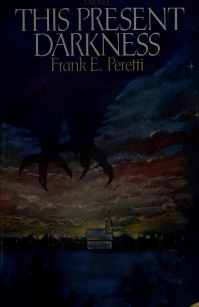 A dark hardcover jacket — 'A NOVEL' in small pale type above the title, 'THIS PRESENT DARKNESS' in large pale serif capitals, 'Frank E. Peretti' beneath it, and a painted night-sky illustration of a monstrous clawed hand reaching down over a small New England-style town with a white church steeple, lit by a fiery orange-red horizon.